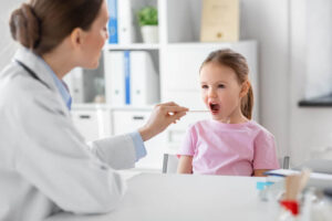 Doctor checking that a young girl has a healthy tongue